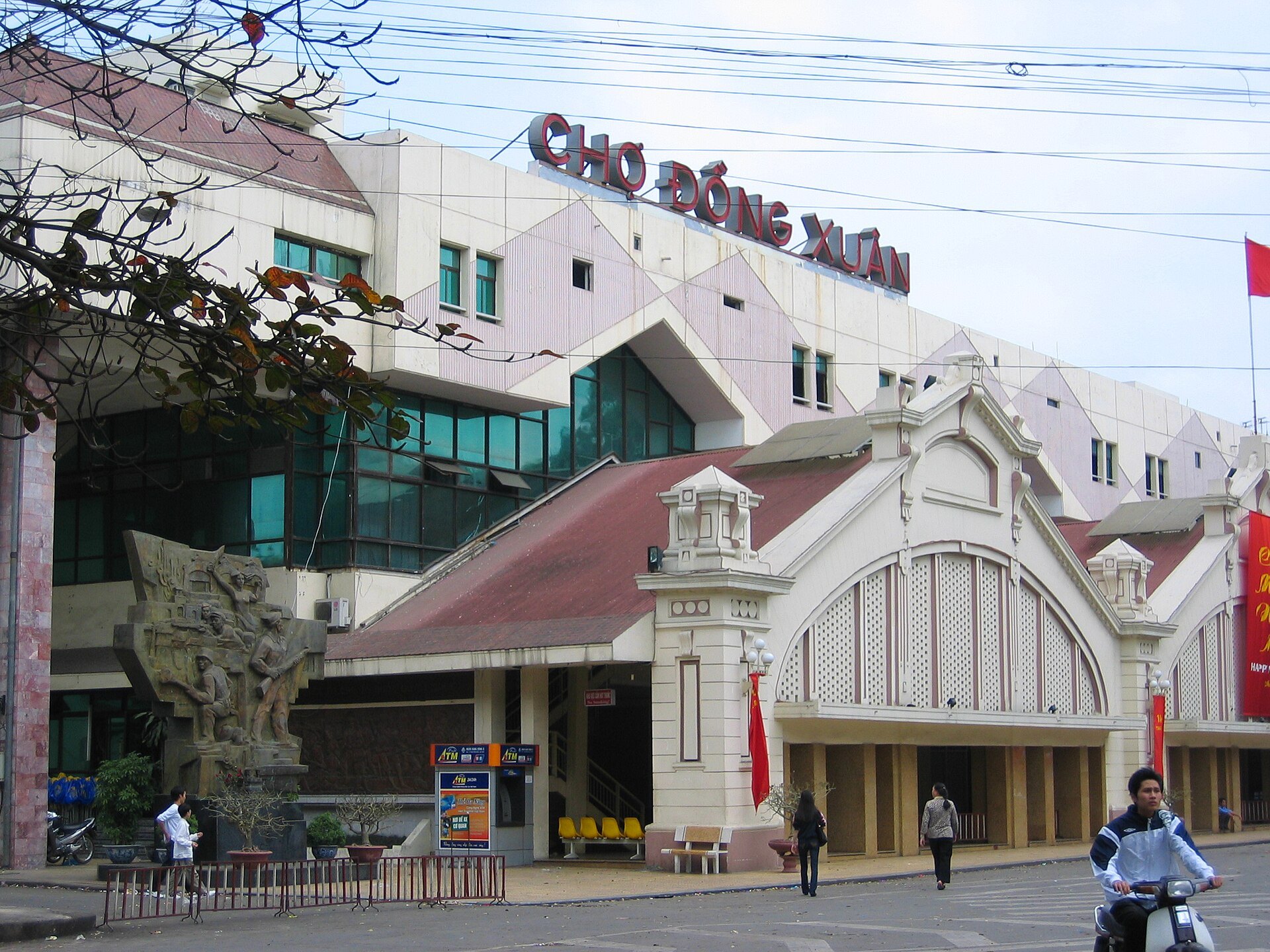 The arched front of Dong Xuan Market with flags above the entrance