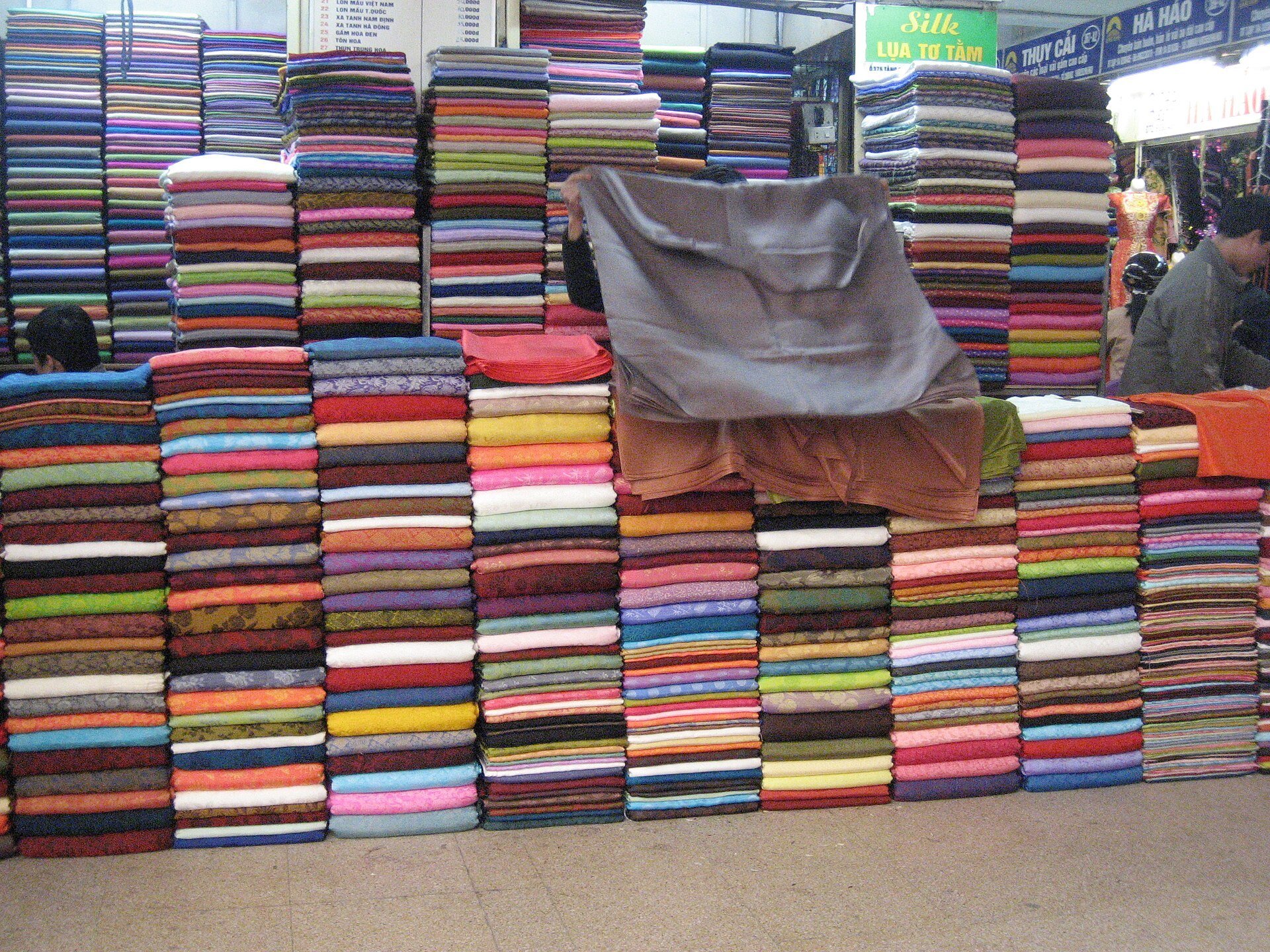 Stacked bolts of coloured fabric on a market stall