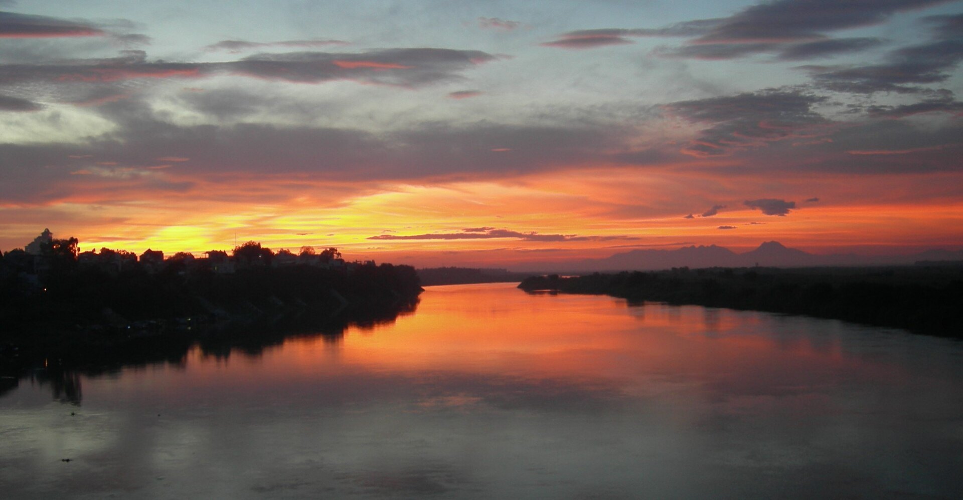 Sunset over the Red River with the Long Bien Bridge in silhouette across it