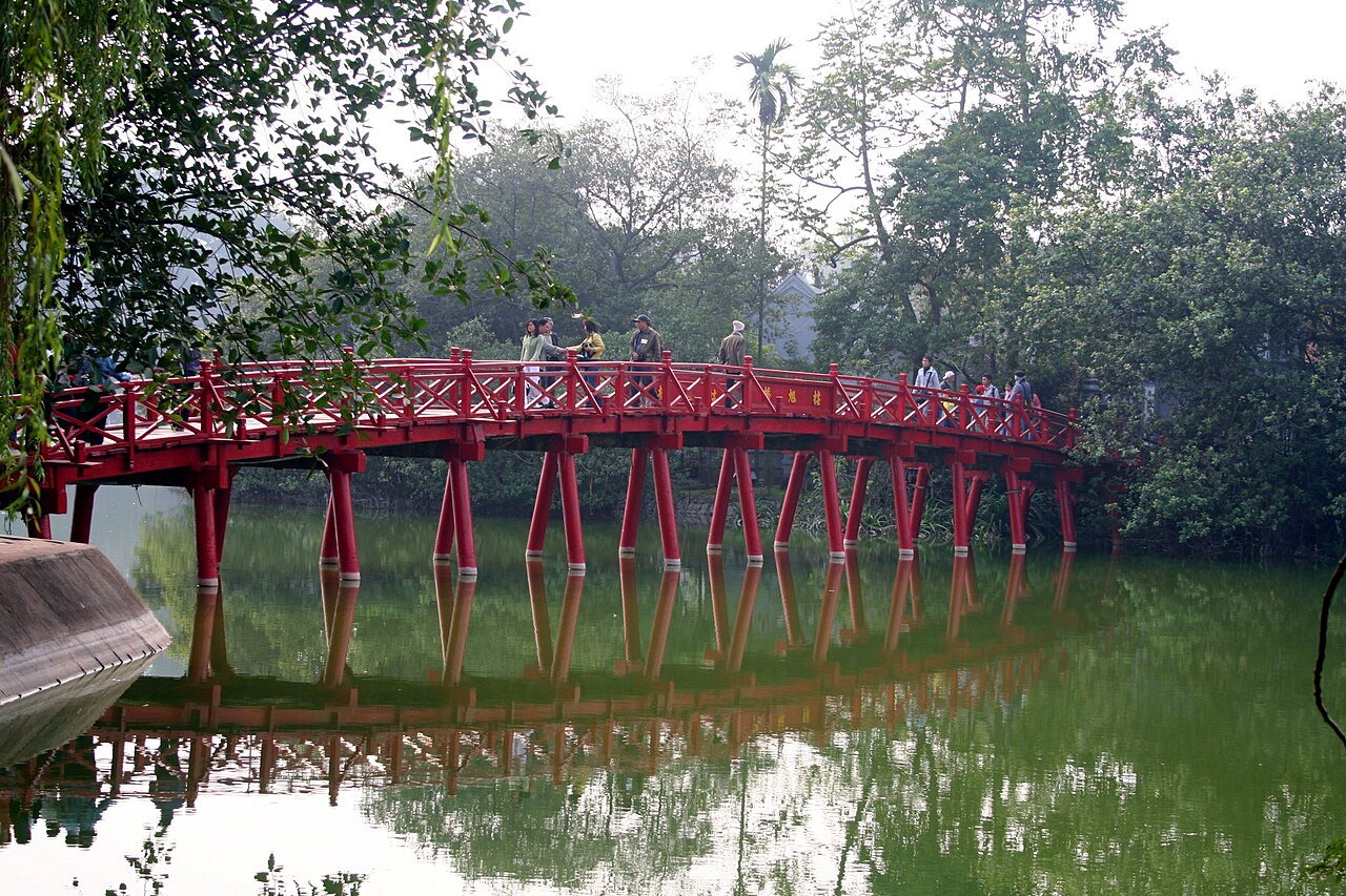 The scarlet Thê Húc bridge arching over the green water to Ngoc Son Temple