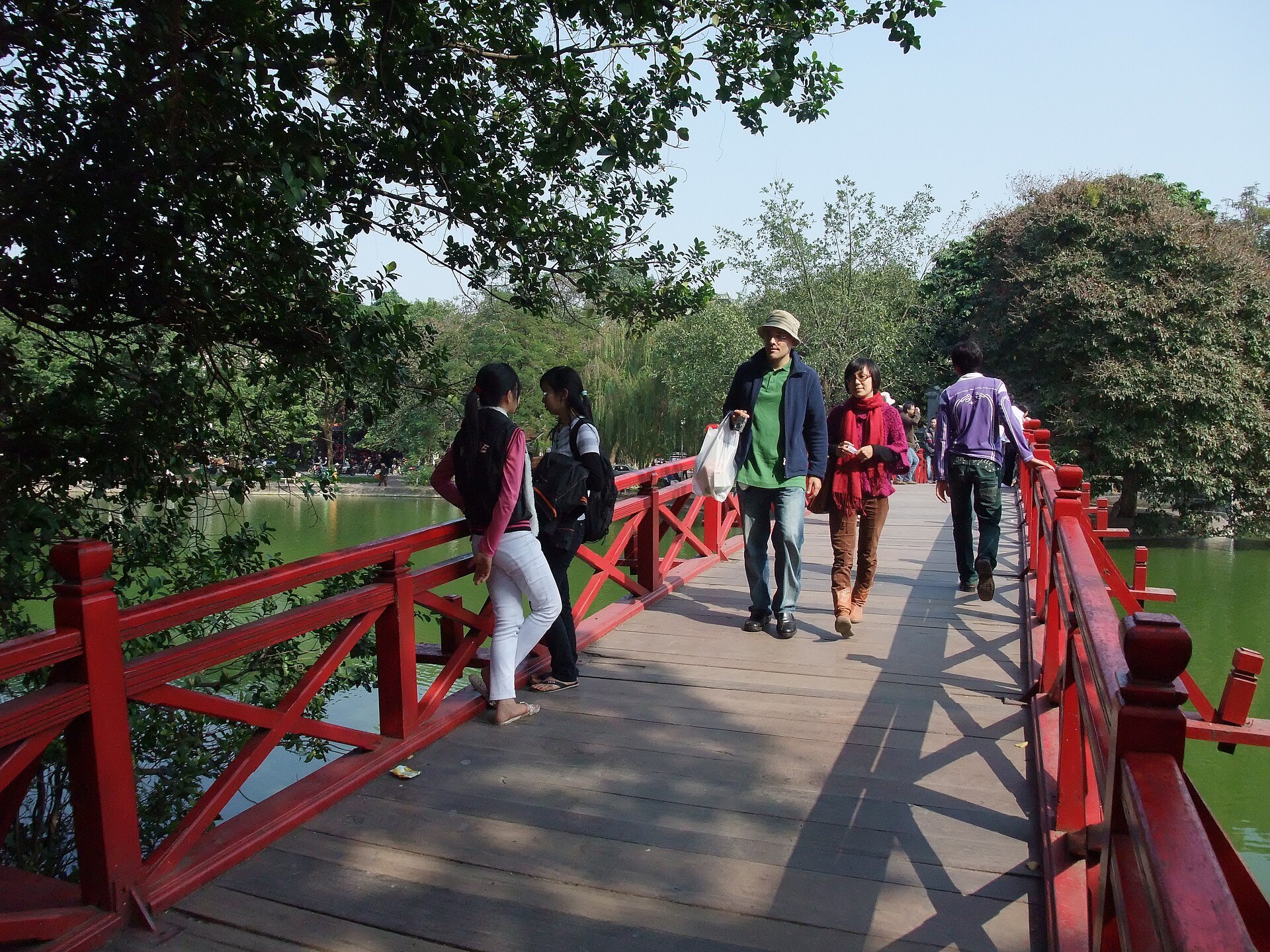 Visitors crossing the red wooden bridge to the temple island