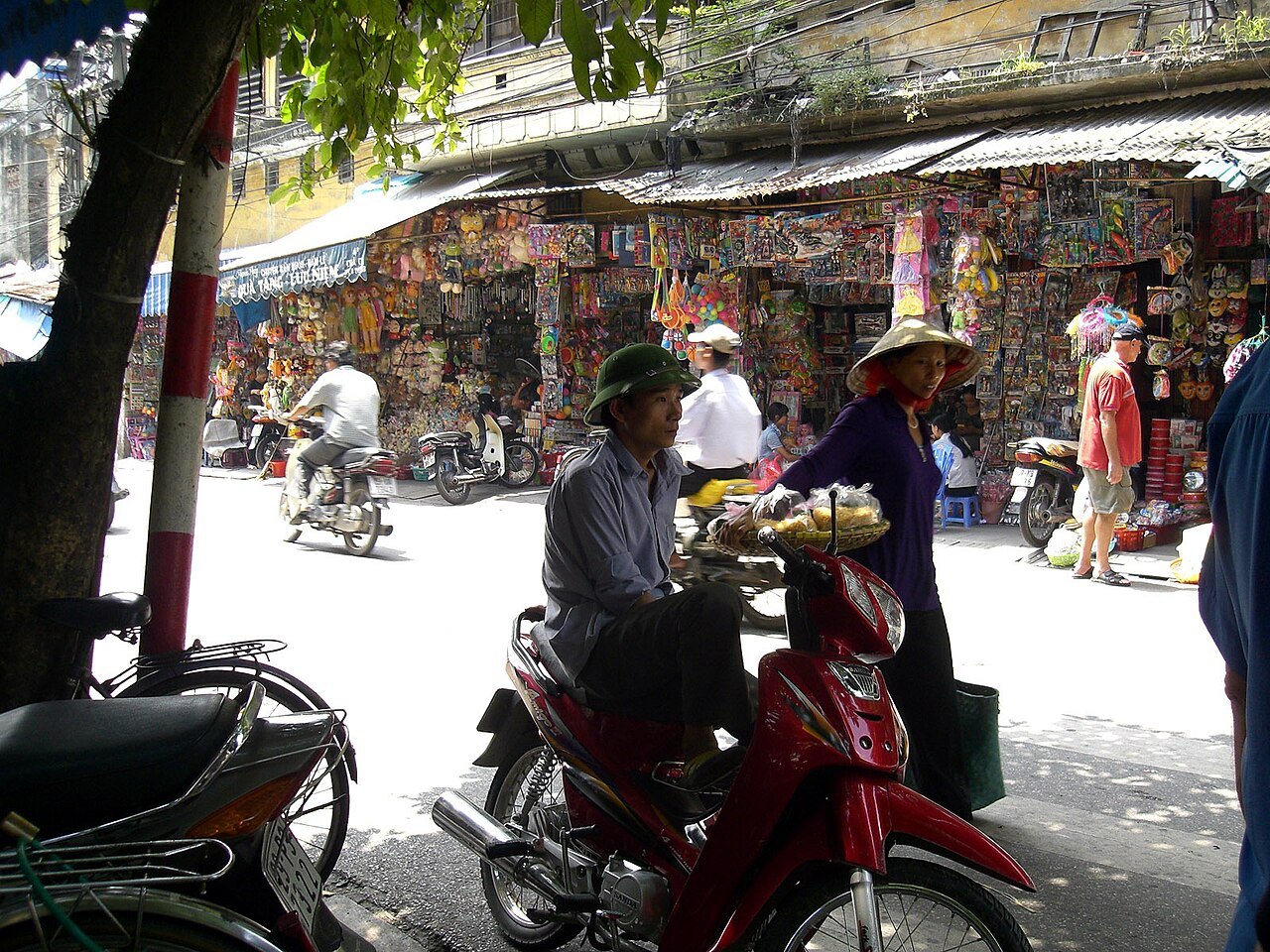 An Old Quarter street with vendors in conical hats and motorbikes passing