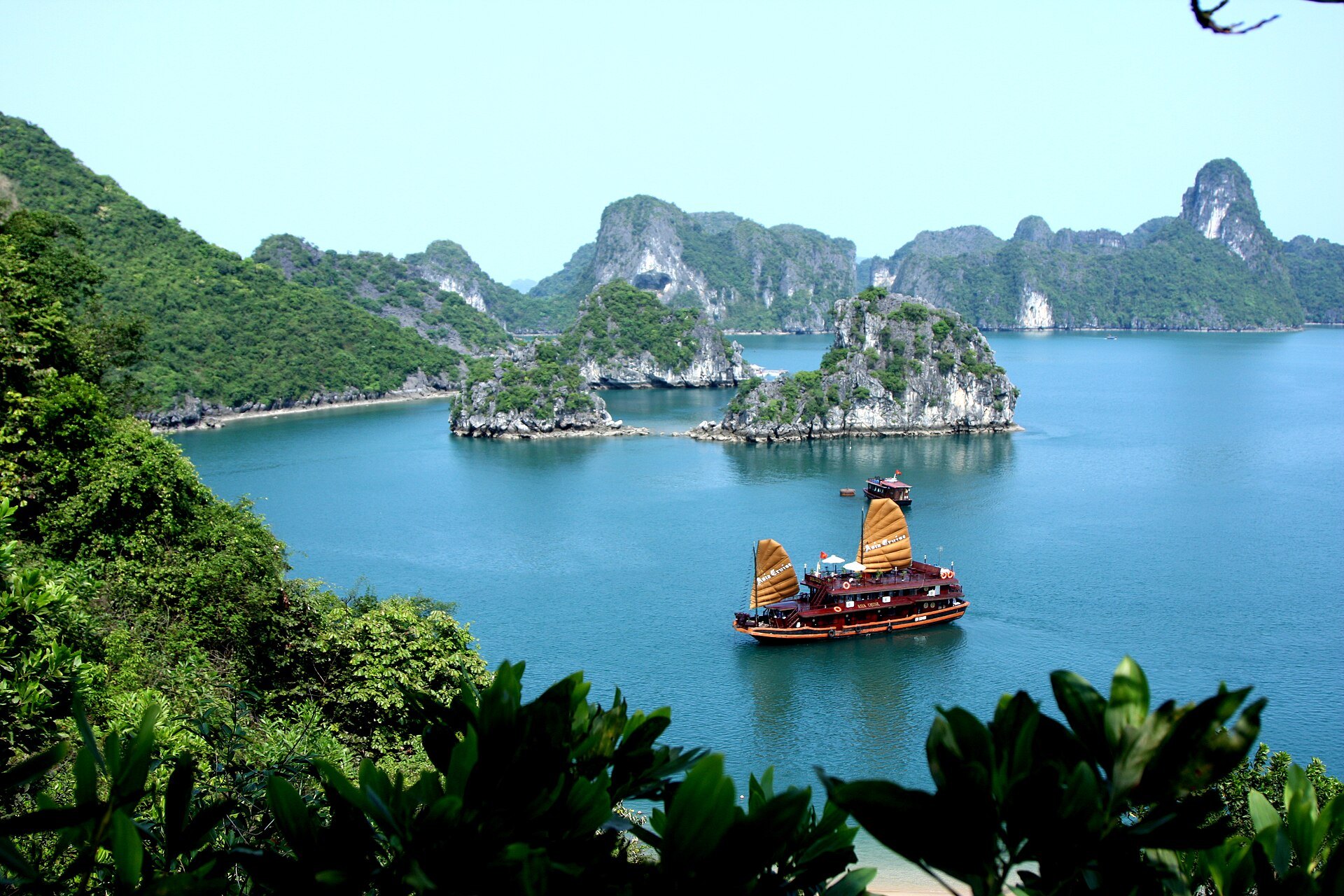 A junk with red sails among the limestone karsts of Ha Long Bay